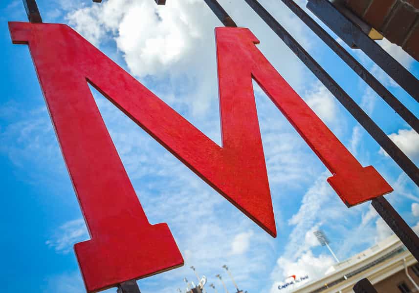 June 2020: Wrought iron red M Gate against brick outside of Maryland Stadium.